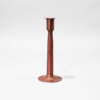 Single hand-hammered copper candlestick centered in a grey background