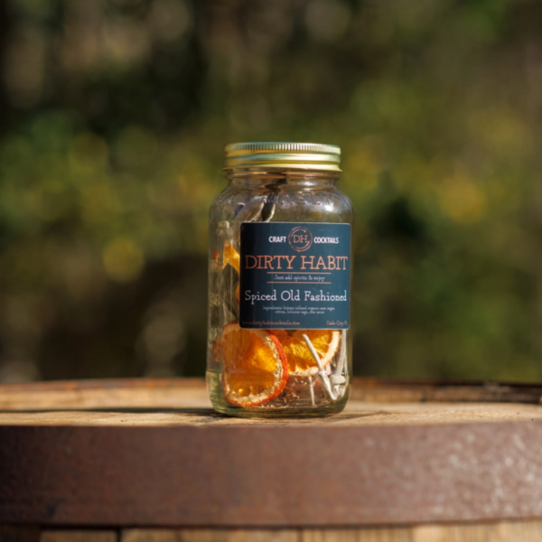 This image shows the Spiced Old Fashion Cocktail Infusion Mix on top of a wine barrel.