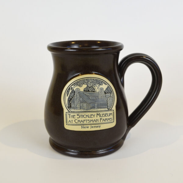 This image shows our deep brown mug produced by Deneen Pottery featuring a blue and white image of the Log Cabin.