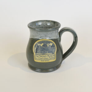 This image shows our sage mug produced by Deneen Pottery featuring a blue and white image of the Log Cabin.