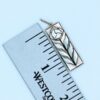This image shows the Craftsman Rose necklace next to a ruler. It shows the piece without the bail is 1.25"