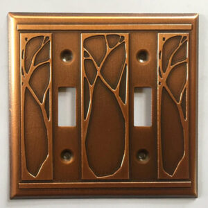 This image shows a copper double light switch plate by James Matteson in the art nouveau pattern. A matching embossed pattern can be found to the left and right of both light switches. Between the two switches is a similar, but wider version of the same design.