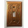 This image shows a copper single light switch plate by James Matteson in the art nouveau pattern. A matching embossed pattern can be found to the left and right of both light switches