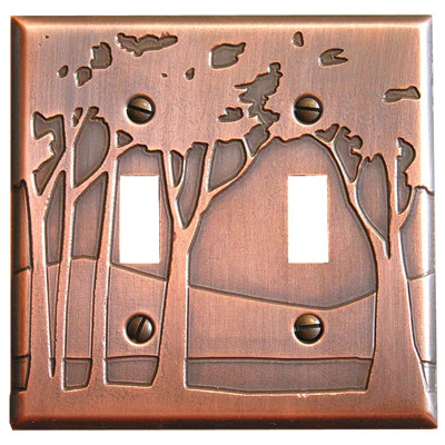 This image shows a copper double light switch plate by James Matteson in the landscape design. Three small trees are to the left of the left switch. One tree is in between the two switches and another tree is to the right of the right switch.