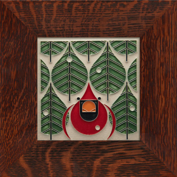 This image shows the coniferous cardinal from Motawi. It is framed in a dark brown frame. There are green trees and one red cardinal on a white background.
