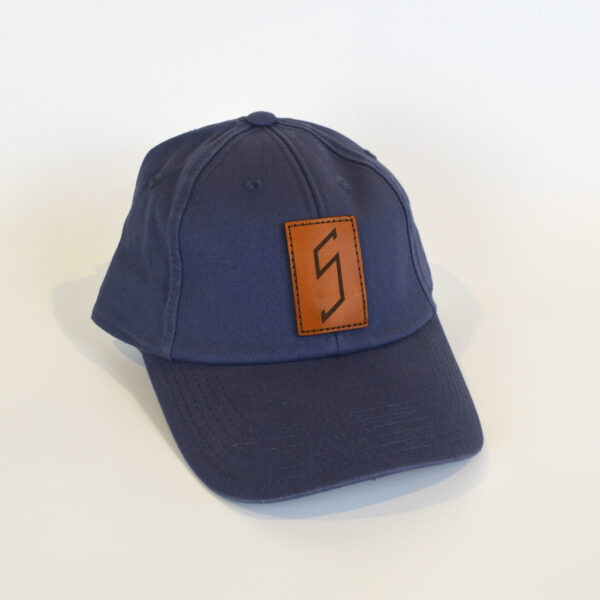 Blue baseball cap with a brown leatherette patch with the "S" found on the staircase in the Log Cabin