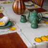 This image shows a modern Stickley Table and Chairs decorated with a beautiful tall ribbed copper vase, with our united crafts tea pot set, plates, runners, placemats and napkins on the table.